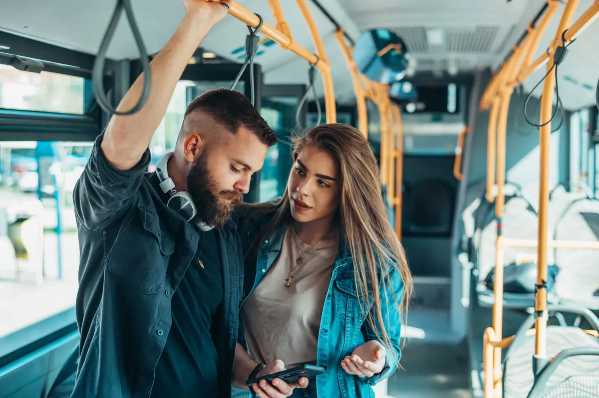 Ein Mann zieht sich emotional zurück, während seine Partnerin in einem Bus versucht, mit ihm zu sprechen. Das Bild symbolisiert den emotionalen Rückzug in einer Beziehung.