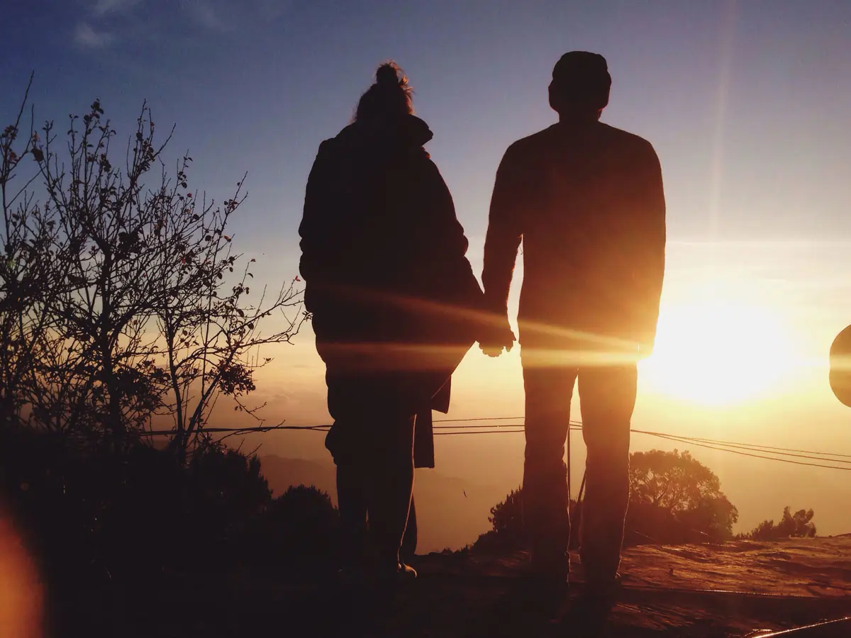 Ein Paar steht Hand in Hand und schaut in einen Sonnenuntergang, symbolisierend für einen Neuanfang und die neue Liebe nach einer langen Ehe.