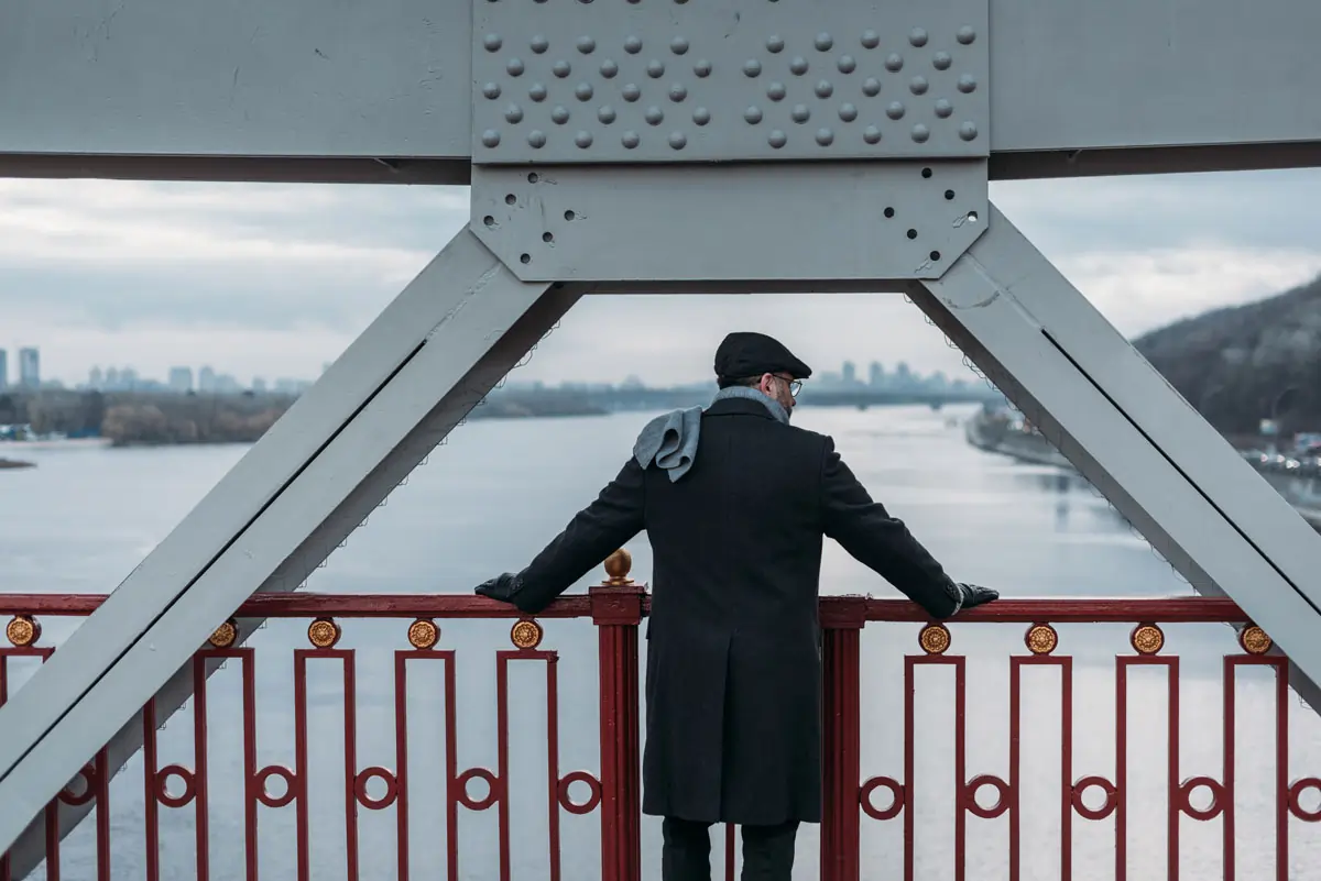 Nachdenklicher Mann auf einer Brücke, der auf einen Fluss schaut – symbolisiert innere Konflikte und die emotionalen Herausforderungen bei einer Verliebtheit trotz Ehe.